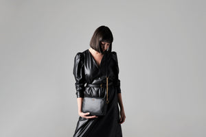 LOM Austrlia | Model wears Libra Cross Body bag in sustainable, vegan, black cactus leather with antique gold hardware.