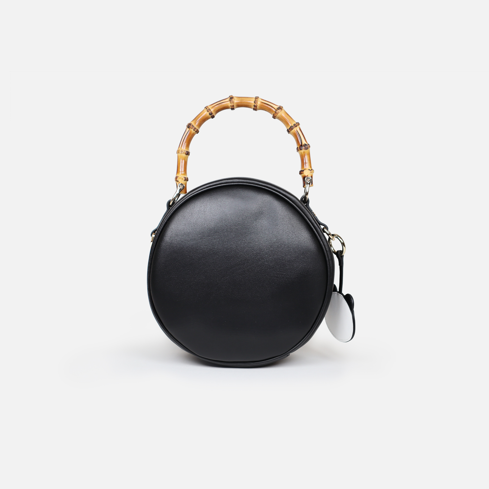 Back of circular handbag with bamboo handle. Made from premium black cactus leather, light gold hardware, black organic cotton lining.